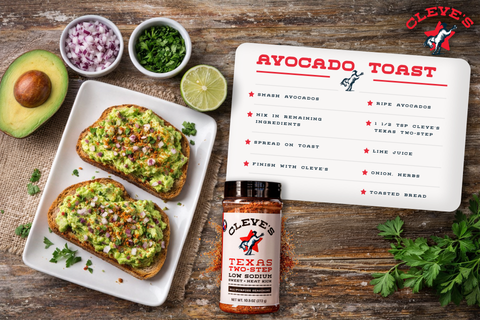 Two slices of Cleve's Avocado Toast topped with red onion and herbs, seasoned with Texas Two-Step, beside a halved avocado and lime