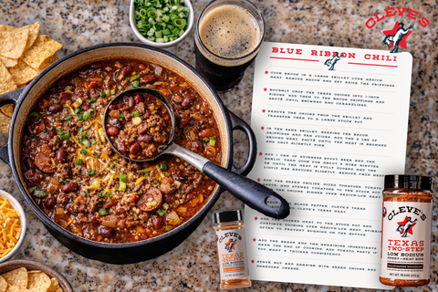 Dutch oven of Cleve's Blue Ribbon Chili with beans, beef, green onions, and cheese, beside bottles of Texas Two-Step and Texas Heat seasoning