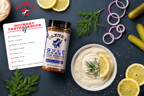 Creamy gourmet tartar sauce topped with fresh dill and a lemon wedge, next to a bottle of Cleve's Gulf Coast Low Sodium seafood seasoning.